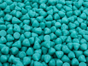 Large pile of cone-shaped plastic vibratory media used for deburring, edge radiusing, cleaning, and surface finishing of manufactured components.