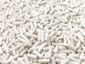 Large pile of cylindrical porcelain vibratory media used for polishing, burnishing, cleaning, and producing bright surface finishes on manufactured components.